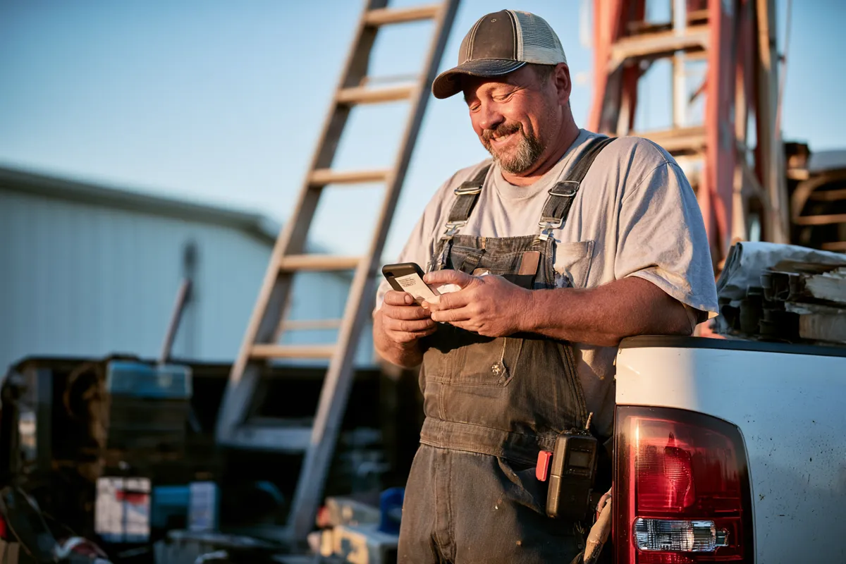 Contractor completing a form on his phone at the tailgate — the request fits inside a work break