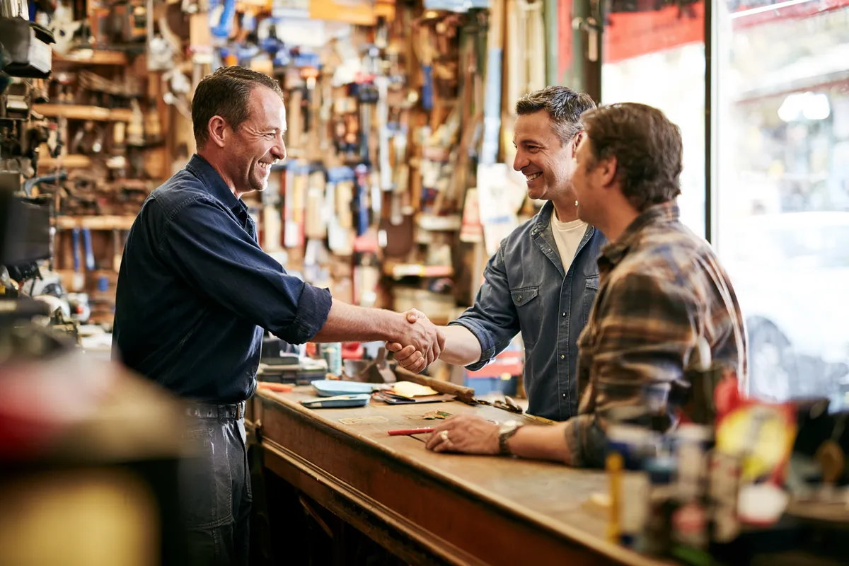 Shop owner and customer shaking hands across the counter — earned trust, documented